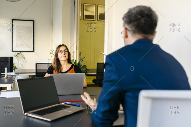 Businessman discussing strategy with businesswoman at office desk