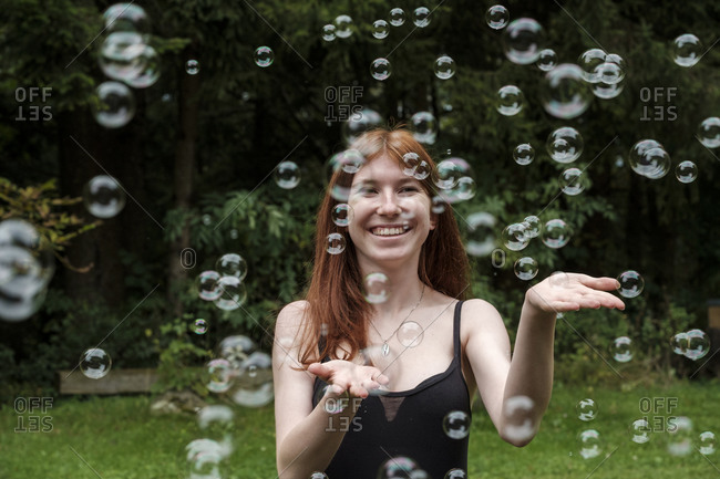Happy woman playing with soap bubbles in yard