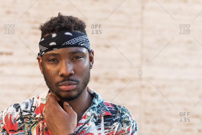 Confident young man wearing headscarf against wall