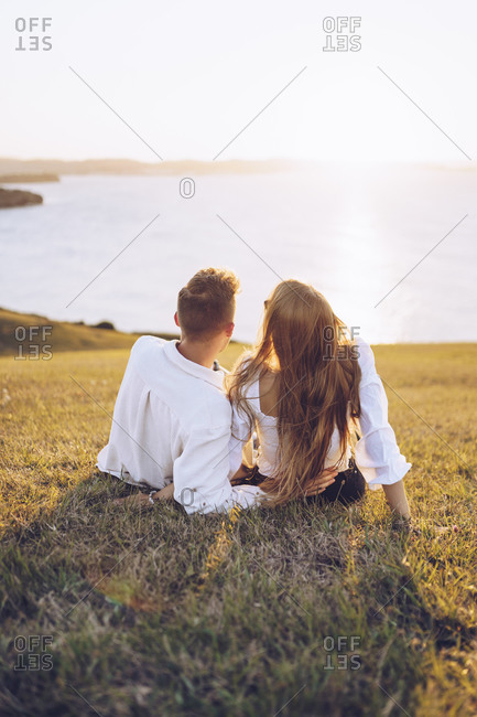 Spain, Gijon, group picture of three little girls sitting at rocky coast  stock photo