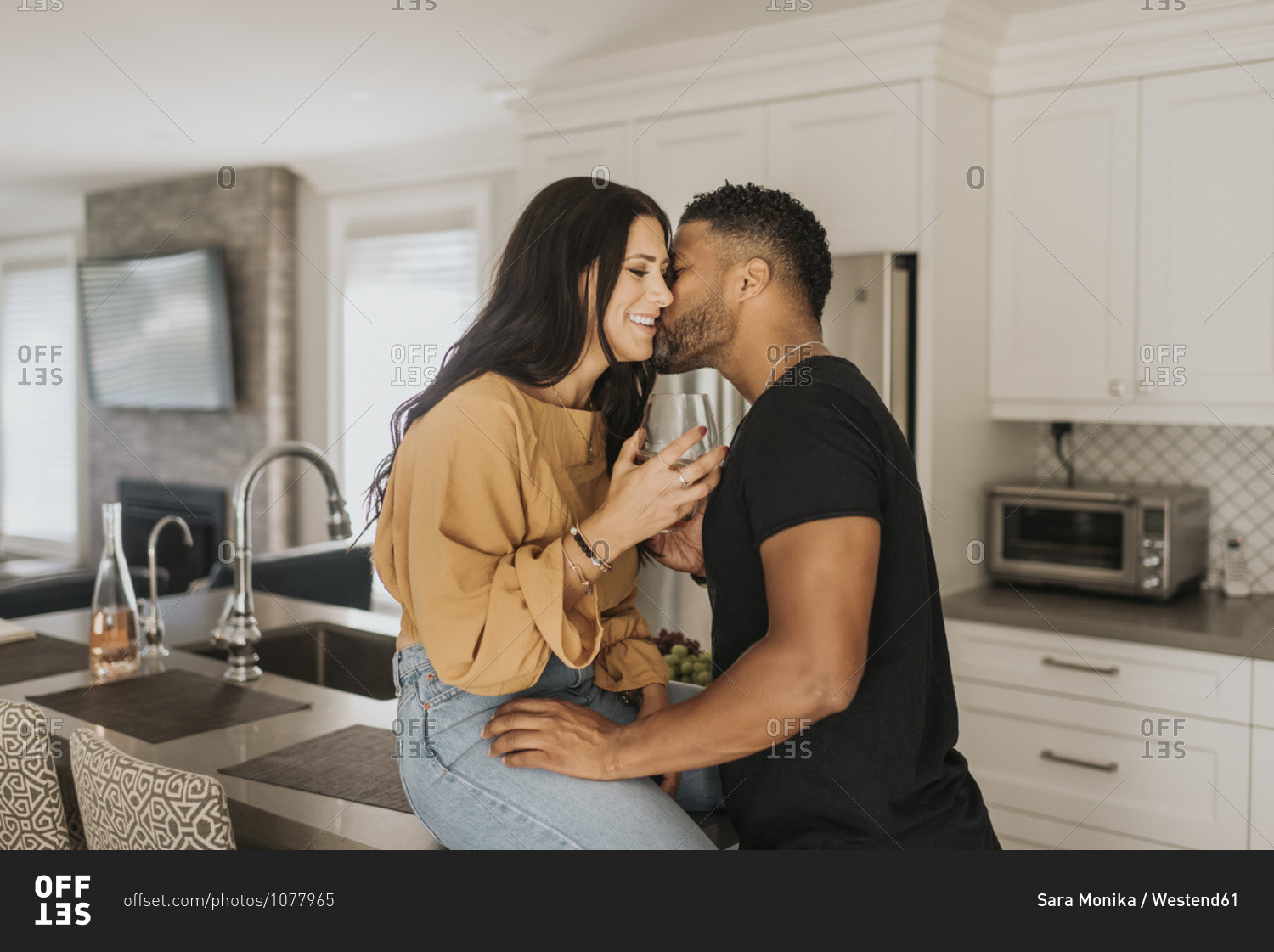 Man kissing woman sitting on kitchen counter at home
