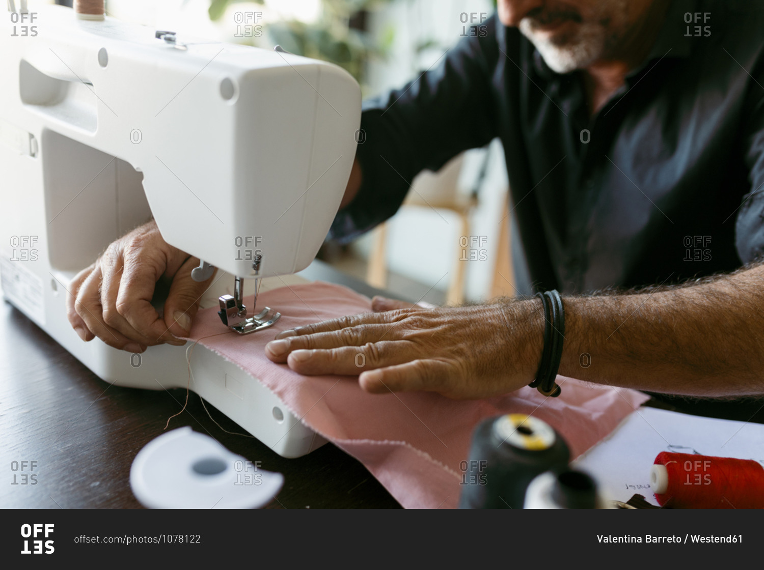 Male costume designer sewing fabric while working in studio