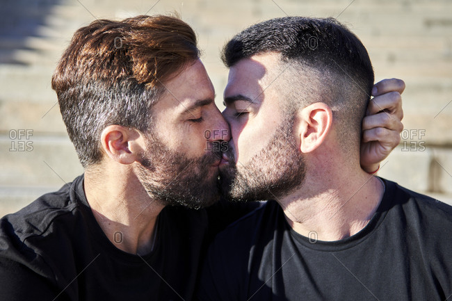 Affectionate homosexual couple kissing on sunny day