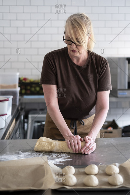Woman in brown apron standing in a cafe kitchen, mixing baking danish pastry dough
