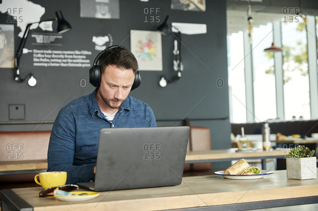 Man seated in a cafe, working on a laptop