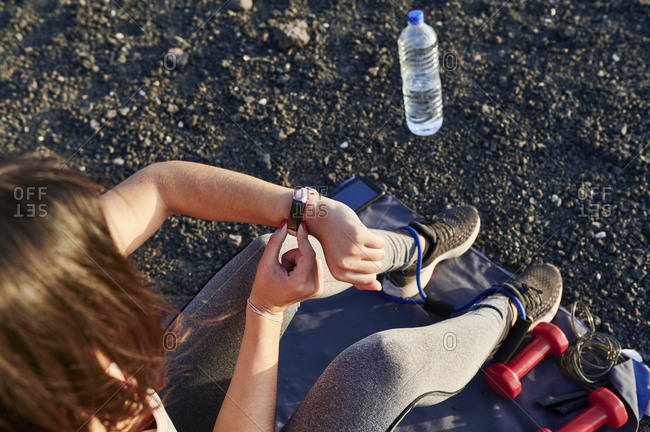 Fit young woman checking her sports watch after an outdoor workout in rocky terrain