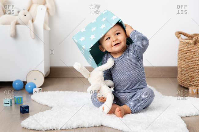 Funny baby in playroom with basket on head