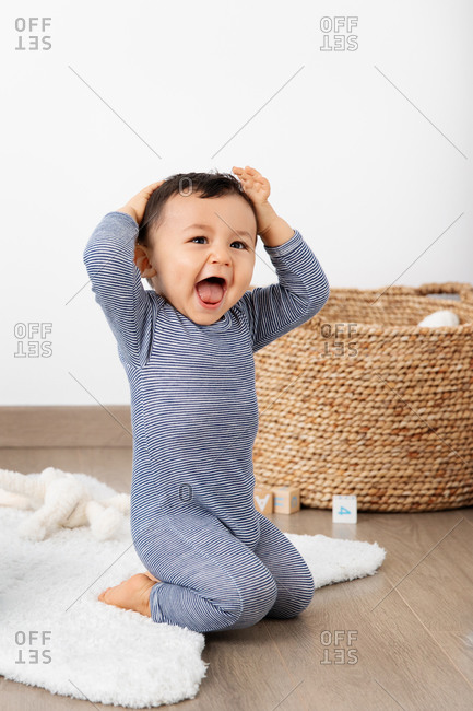 Laughing baby with hands on his head