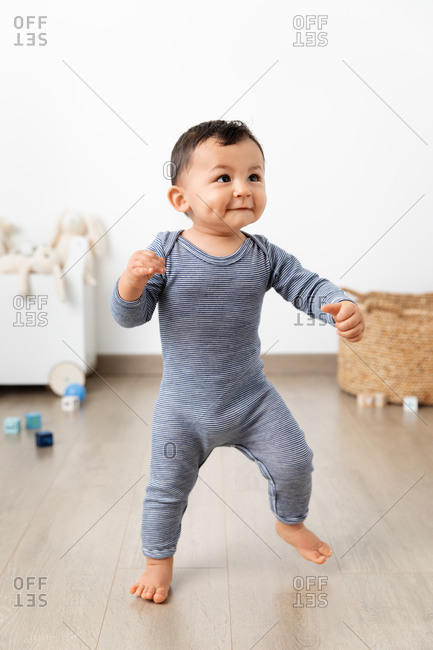 Happy toddler making first steps in playroom
