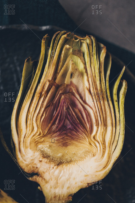 Cut in half artichoke on dark plate viewed from above
