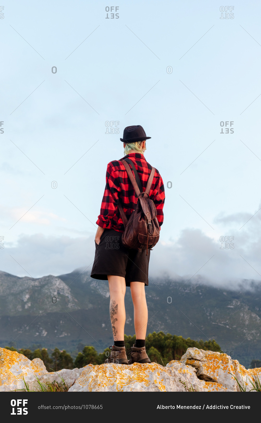 Back view low angle of carefree explorer standing on rocky hill in highlands and enjoying freedom with outstretched arms during adventure