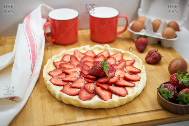 Homemade vegan cake garnished with fresh sweet strawberries served on table in bright kitchen
