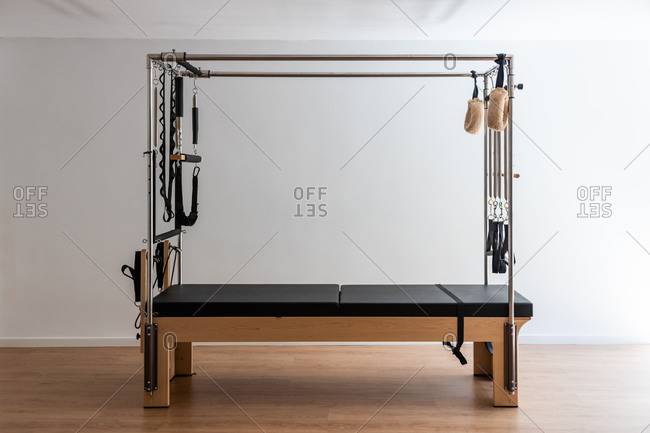 Contemporary pilates cadillac reformer placed on wooden floor in bright sports club at daytime
