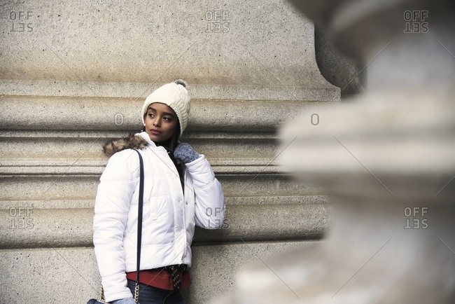 Confident African American female wearing warm trendy clothes standing on street of New York and looking away