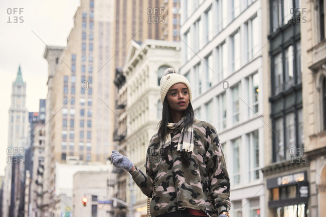 Young African American female in camouflage outfit standing on street in New York and looking away