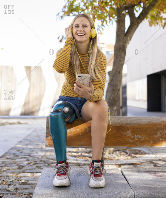 Front view of smiling female with bionic leg prosthesis sitting in