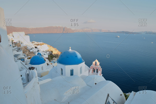 Spectacular scenery of city with white church with round shaped blue dome located in front of sea on Santorini
