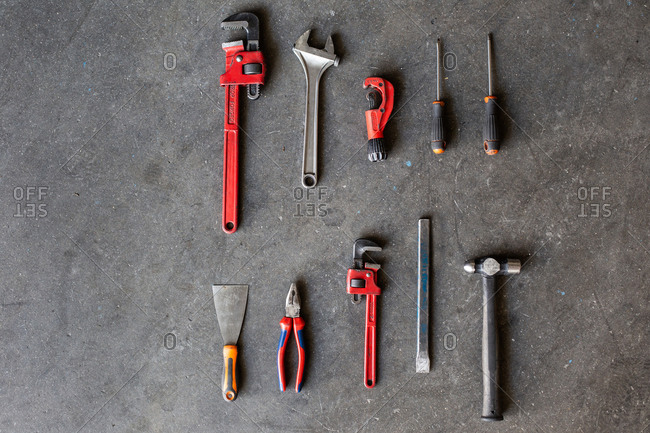 Top view of shabby metal repair tools arranged in rows on floor of garage