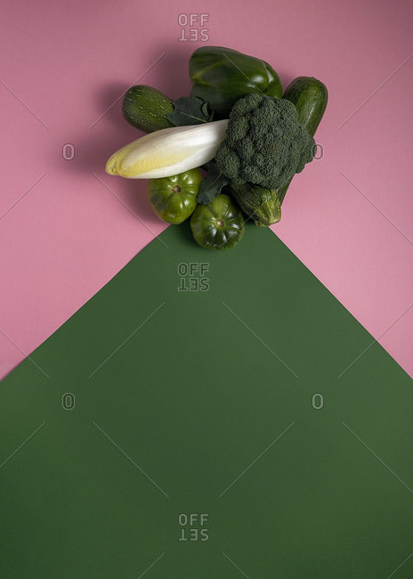 From above composition of green broccoli and peppers with tomatoes and zucchini arranged on colorful background