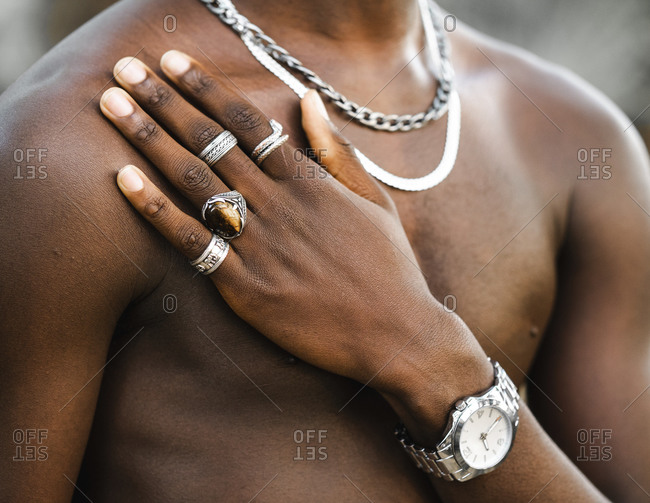 Unrecognizable crop African American male with naked torso showing hand with trendy silver rings