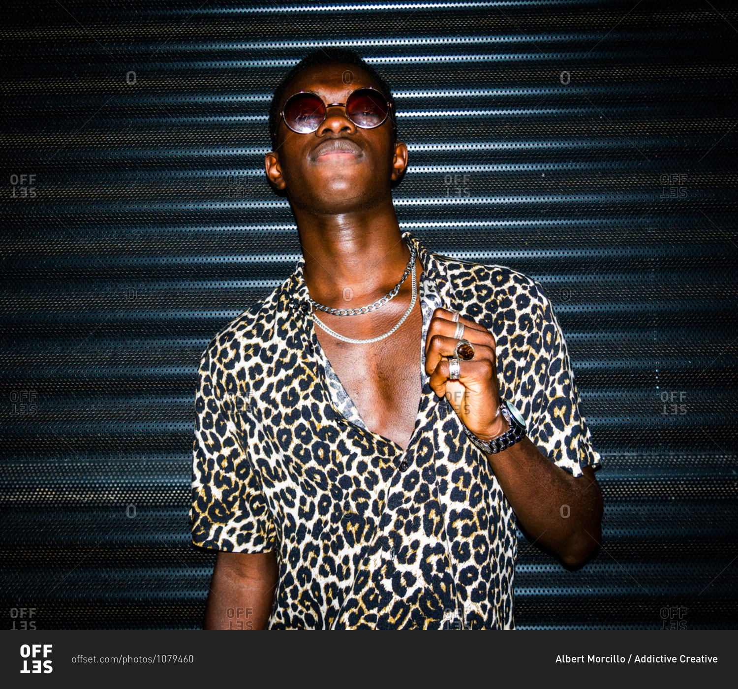 Determined African American male in summer shirt with leopard print standing in street at night and looking at camera