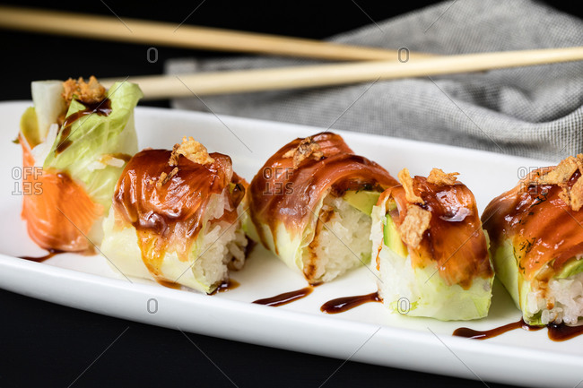 Closeup of palatable rolls filled with fresh turnip and garnished with teriyaki sauce