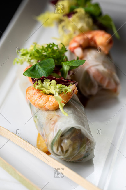 Closeup of delicious duck cannelloni garnished with shrimps and greenery and served on plate in Asian restaurant