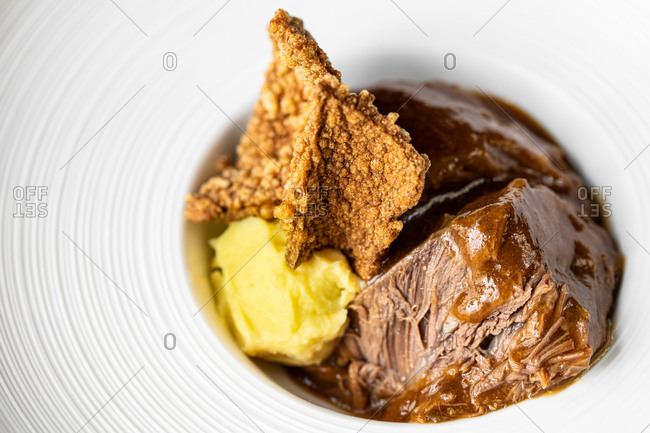Closeup of appetizing beef with sauce garnished with parsnip and ginger in luxury restaurant