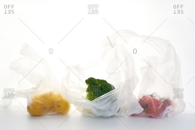 Still life with food in plastic bags backlit on white background