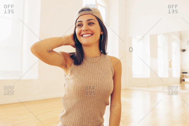 Tender female wearing stylish clothes standing on floor in bright spacious room and looking away