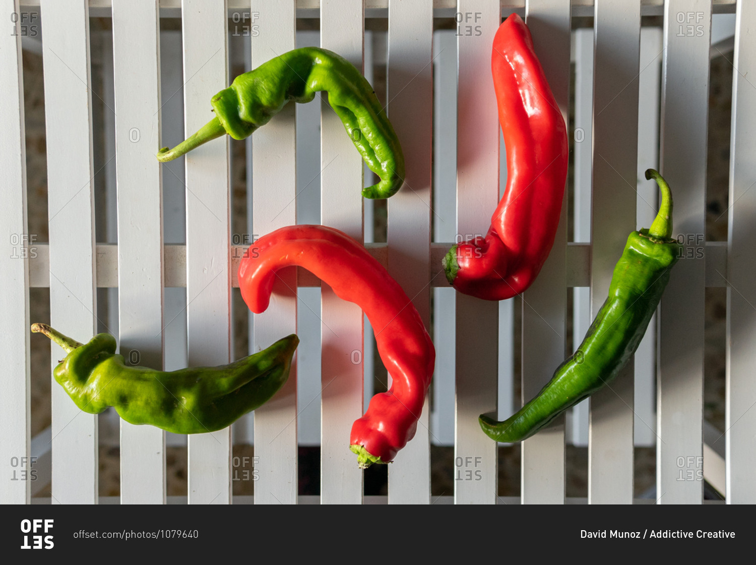 Top view composition with bright red and green bio organic chili peppers arranged on white plank surface