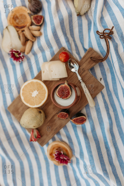 From above delicious cocoa drink and sweet tartlet placed on wooden cutting board on blanket in park for picnic