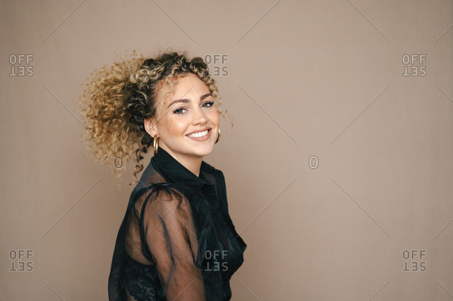 Optimistic female with curly hair smiling in studio and looking at camera