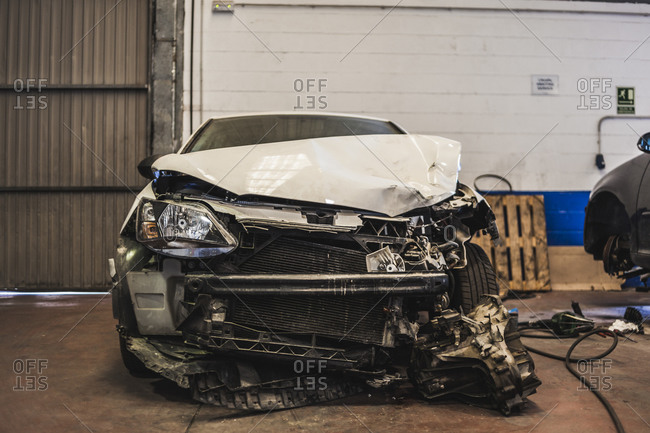 Modern vehicle with wrecked front parked inside spacious professional garage for repair works