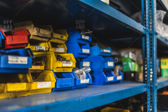 Colorful crates with nails and screws stacked on metal shelf inside professional garage