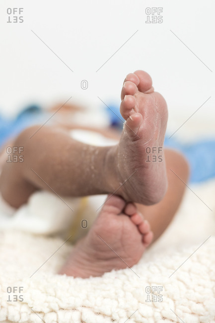 Unrecognizable close up of adorable newborn baby feet lying on soft blanket