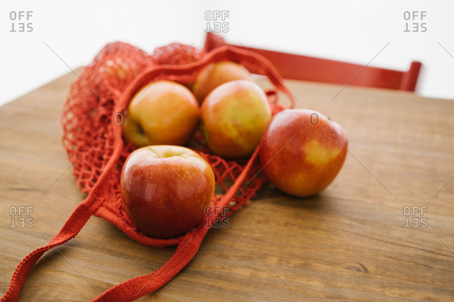 Top view of fresh apples in cotton eco friendly sacks placed on wooden table