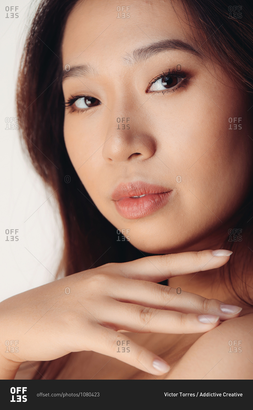Portrait of naked young Chinese woman looking at camera over white background stock photo - OFFSET