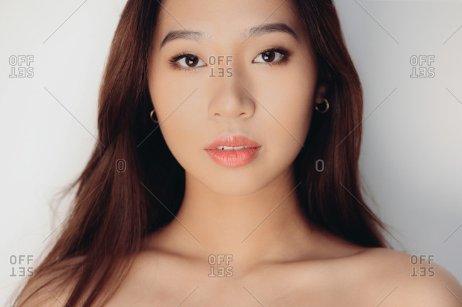 Portrait of naked young Chinese woman looking at camera over white background