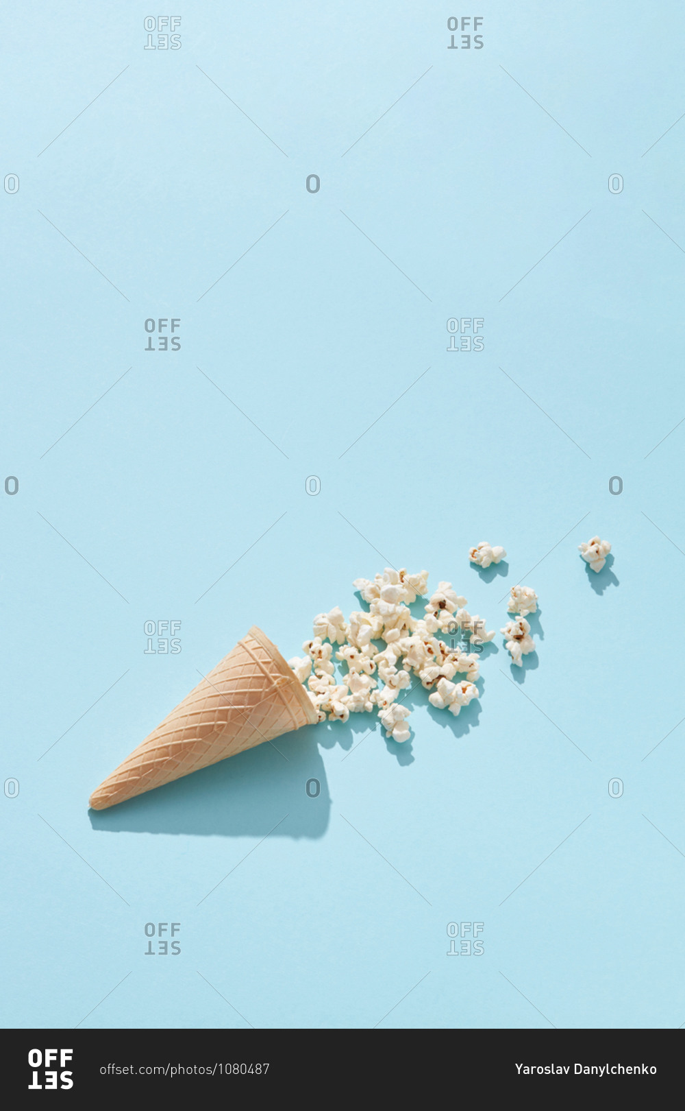 Tasty cooked classic popcorn in cone on blue background, copy space