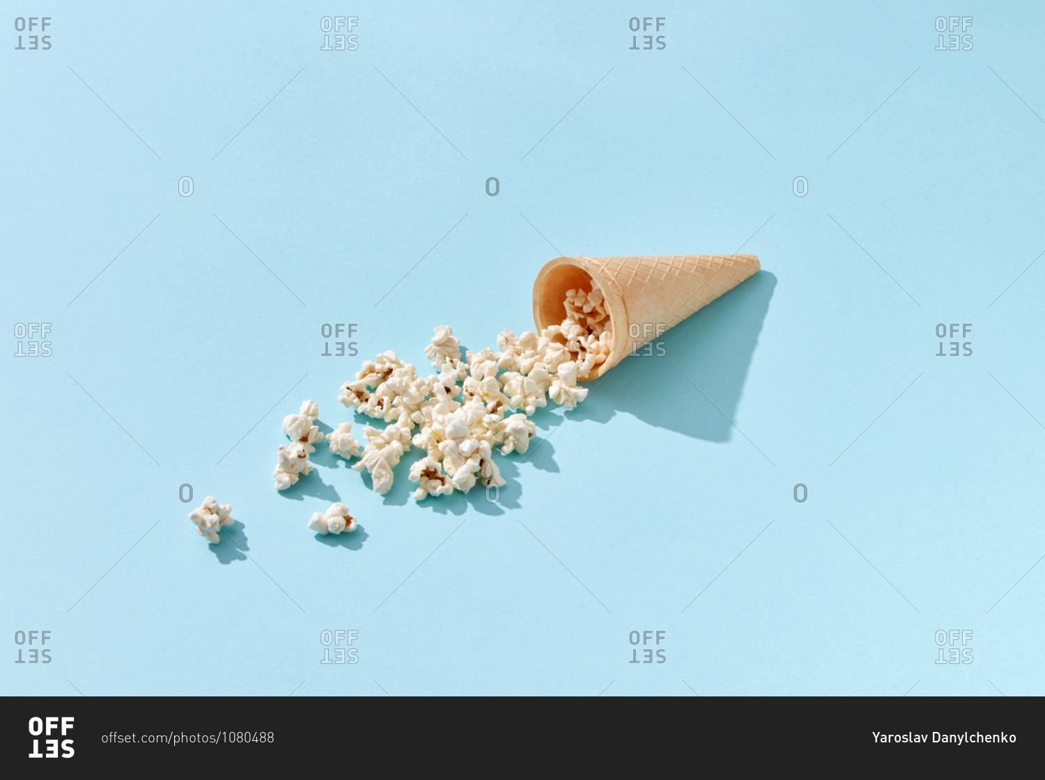 Tasty cooked classic popcorn in cone on blue background