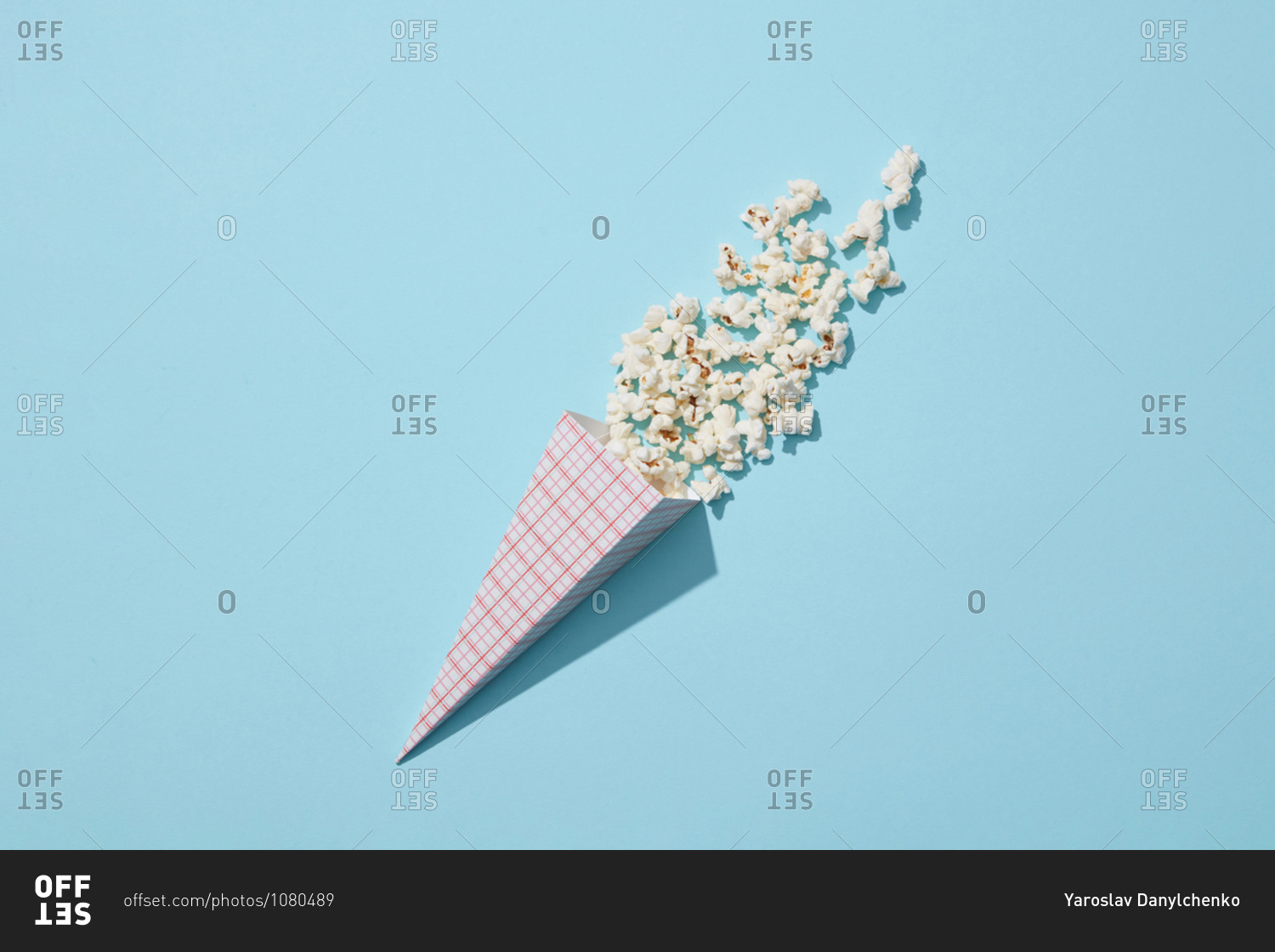 Tasty cooked classic popcorn in paper cone on blue background