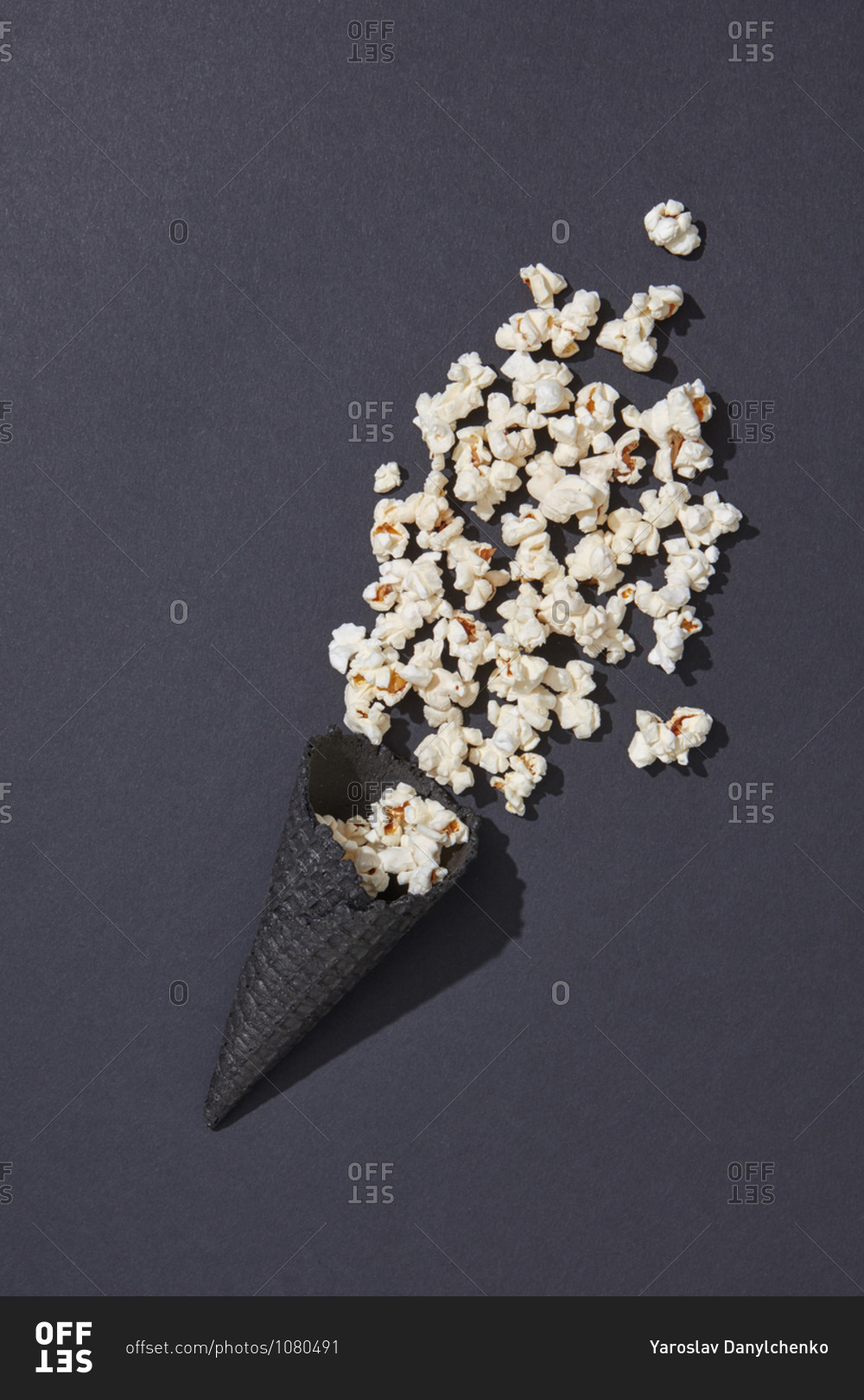 Tasty cooked classic popcorn in black cone on black background