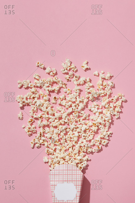 Delicious cooked popcorn in carton container on pink background, flatlay