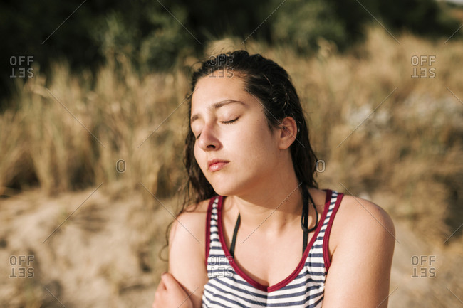 Young teenage girl sunbathing with closed eyes on the beach