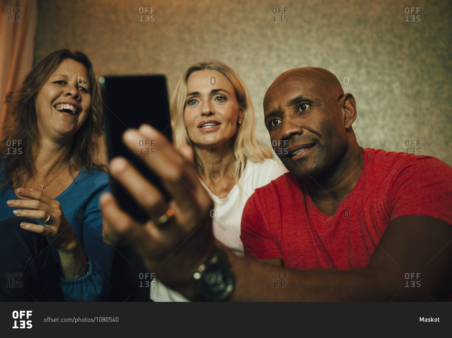 Smiling man showing smart phone to women during sporting event