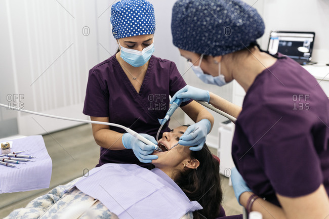 Female dentists wearing protective face mask examining a patient.