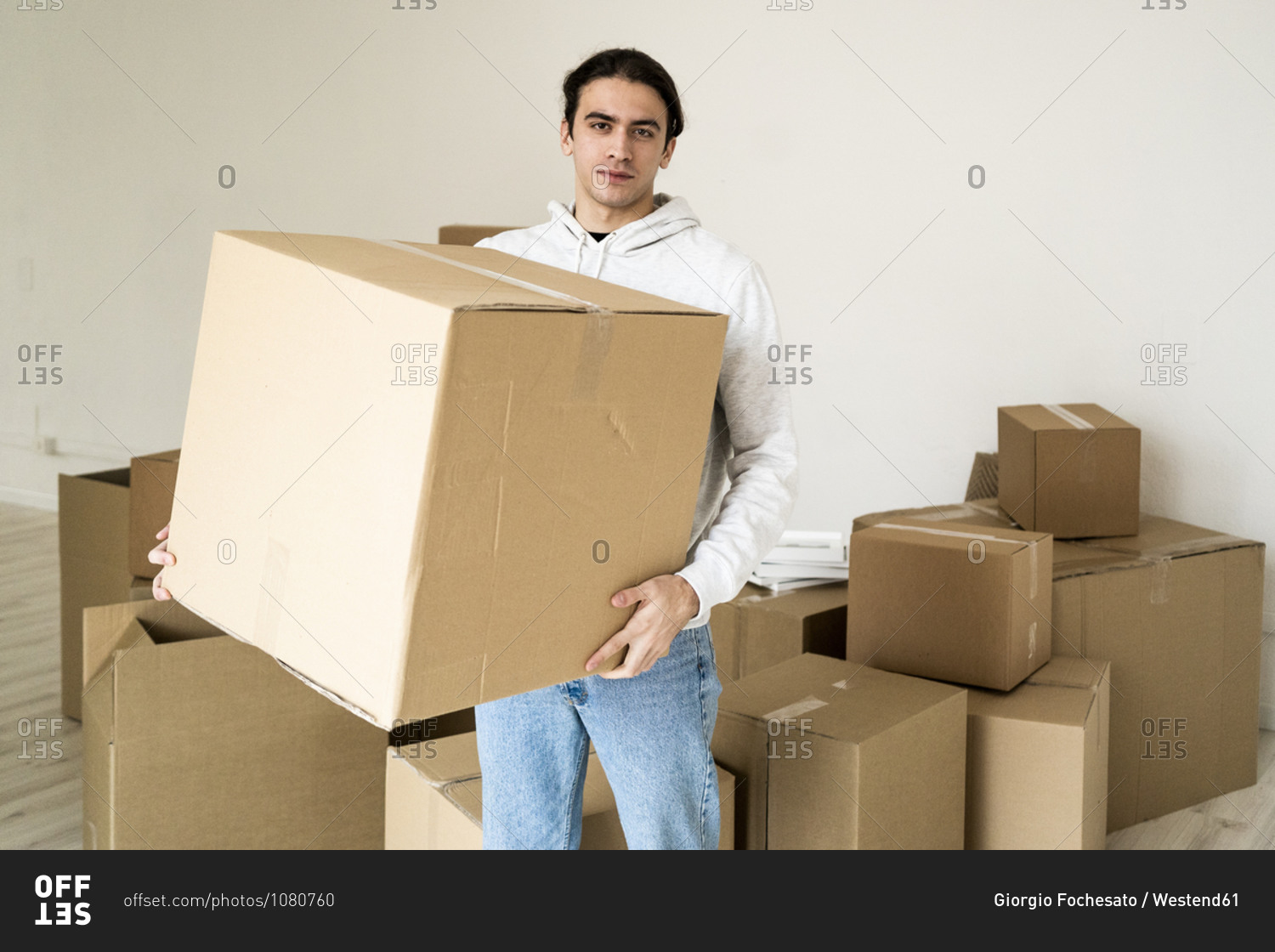 Young man carrying cardboard box in new house