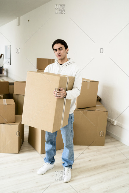 Young man carrying cardboard box while standing in new house
