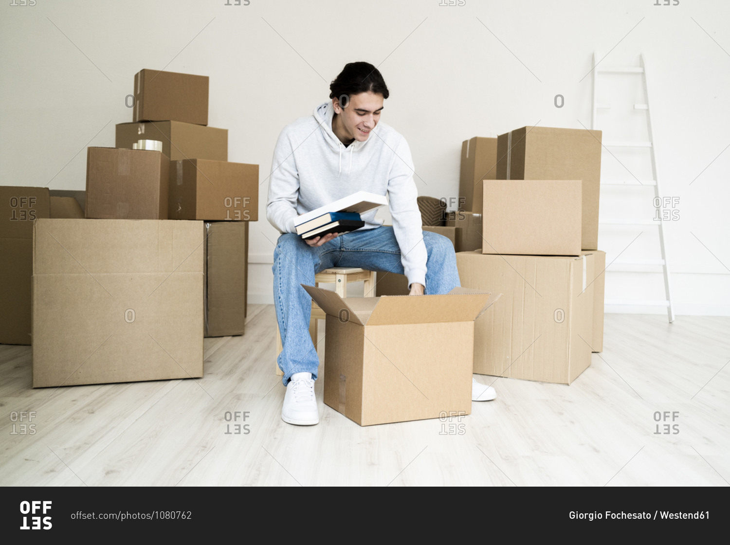 Young man removing books while unpacking box in new house